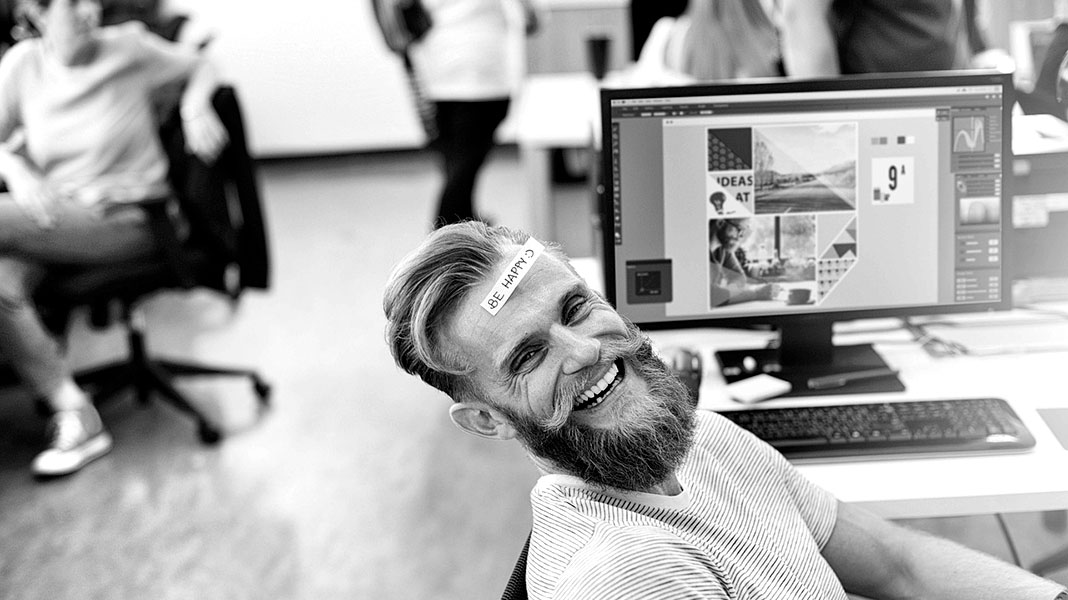 Trabajador sonriendo en una oficina con ordenadores